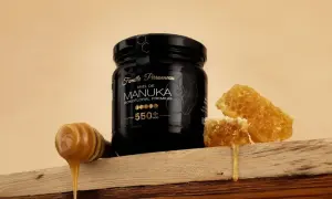 Un pot de miel de Manuka 550+ MGO, avec des rayons de miel et une cuillère à miel dégoulinante. Ce miel de manuka dangereux pour les bactéries, est un trésor de la nature.
