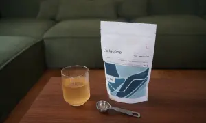 Un verre de boisson au collagène et sa dosette à côté d'un sachet, idéal pour savoir quand prendre le collagène.