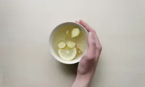 Une main tient un bol de tisane au citron et au gingembre, une boisson réconfortante pour comment prendre soin de son foie.