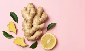 Gingembre anti inflammatoire, citron et feuilles vertes sur fond rose. Un remède naturel pour le bien-être.