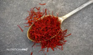 Une cuillère remplie de stigmates de safran rouge vif sur fond gris. Le safran est une épice précieuse, mais il existe des contre-indications à son usage.