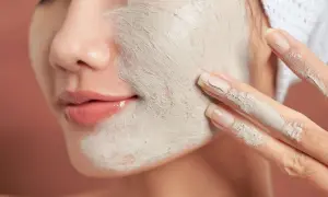 Une femme applique un masque d'argile sur son visage. Un tuto argile débutant pour une peau éclatante.