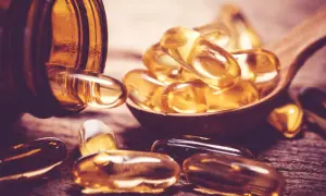 Gélules dorées sur une cuillère en bois, évoquant la vitamine D sans soleil.