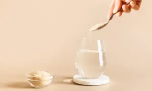 Une cuillère verse du psyllium dans un verre d'eau, une solution naturelle pour soulager la diarrhée.