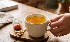 Une tasse de thé fumant au safran, avec un petit pot de pistils. Attention, le safran peut présenter un danger s'il est consommé en excès.