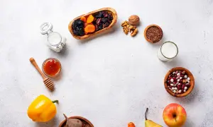 Un assortiment d'aliments bons pour l'estomac et les intestins : fruits secs, noix, graines de lin, haricots, lait, miel, poivron, betterave, pomme et poire.