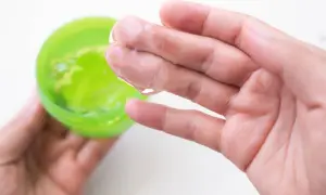 Main tenant une main, une autre prélève un gel transparent d'un pot vert. Attention à l'allergie à l'aloe vera.