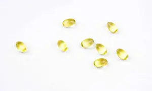 Plusieurs gélules d'oméga 3 DHA, connues pour leurs bienfaits sur la santé, sont dispersées sur un fond blanc.