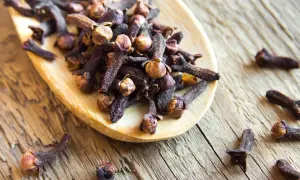 Girofles sur une cuillère en bois, évoquant leur potentiel dans la gestion de l'hypertension.