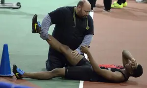 Un athlète reçoit des soins pour une jambe, peut-être pour comment éviter les crampes pendant l'effort.