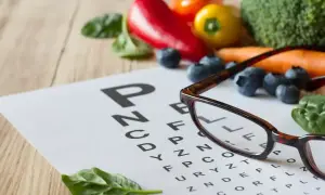 Lunettes sur un tableau d'optométrie entouré de fruits et légumes. La lutéine, présente dans ces aliments, est bénéfique pour la vision.