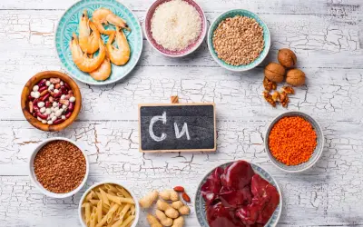 Assiette de crevettes, bols de riz, lentilles, haricots, pâtes, cacahuètes, noix, foie et un tableau noir avec "Cu" pour les cuivre bienfaits.