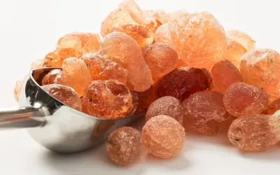 Grains ambrés de gomme arabique, aussi appelée fibre d'acacia, dans une cuillère métallique.