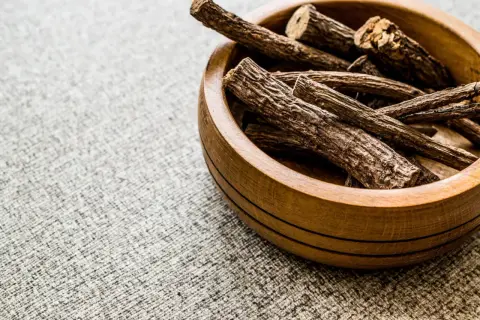 Racines de réglisse dans un bol en bois, évoquant les bienfaits du réglisse pour la santé.