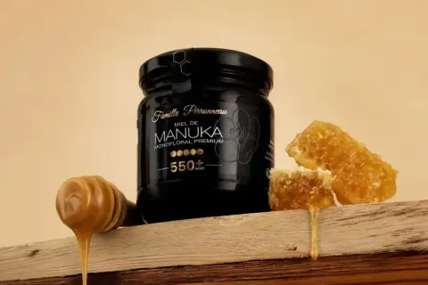 Un pot de miel de Manuka 550+ MGO, avec des rayons de miel et une cuillère à miel dégoulinante. Ce miel de manuka dangereux pour les bactéries, est un trésor de la nature.
