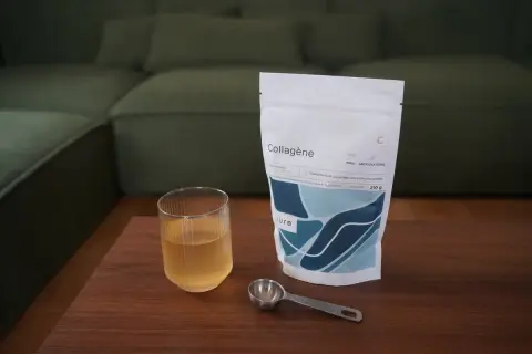 Un verre de boisson au collagène et sa dosette à côté d'un sachet, idéal pour savoir quand prendre le collagène.