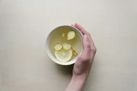 Une main tient un bol de tisane au citron et au gingembre, une boisson réconfortante pour comment prendre soin de son foie.