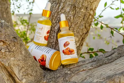 Trois flacons d'huile d'argan, aux multiples huile d'argan bienfaits, reposent sur une branche d'arbre.