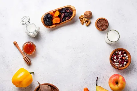 Un assortiment d'aliments bons pour l'estomac et les intestins : fruits secs, noix, graines de lin, haricots, lait, miel, poivron, betterave, pomme et poire.