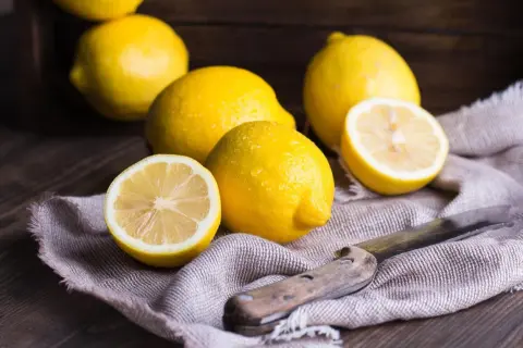 Citrons frais, coupés et entiers, sur un tissu, évoquant un remède de grand-mère contre le rhume de cerveau.