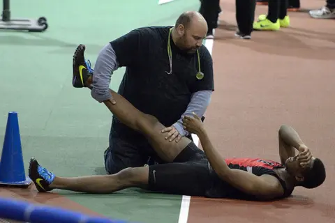 Un athlète reçoit des soins pour une jambe, peut-être pour comment éviter les crampes pendant l'effort.