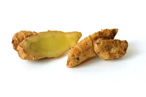 Racines de galanga coupées, montrant leur chair jaune pâle. Le galanga est parfois étudié pour ses bienfaits potentiels sur l'hypertension.