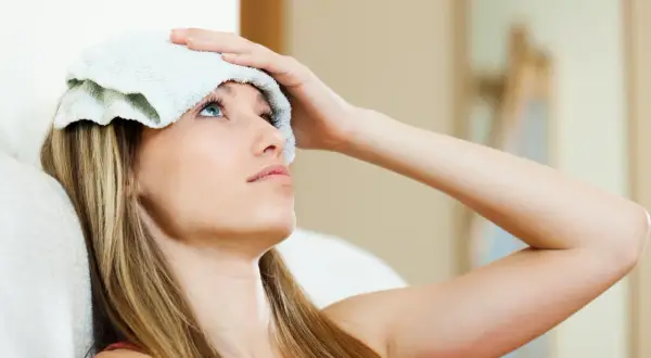 Femme avec une compresse froide sur le front, cherchant des solutions pour la gueule de bois que faire.