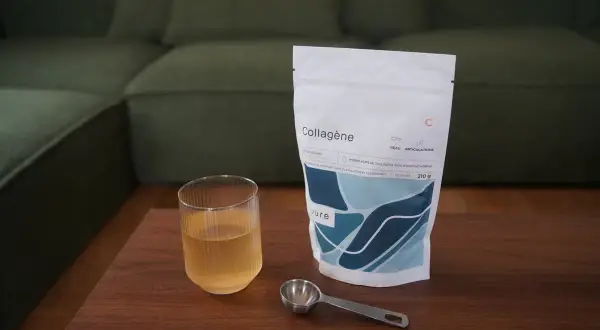 Un verre de boisson au collagène et sa dosette à côté d'un sachet, idéal pour savoir quand prendre le collagène.