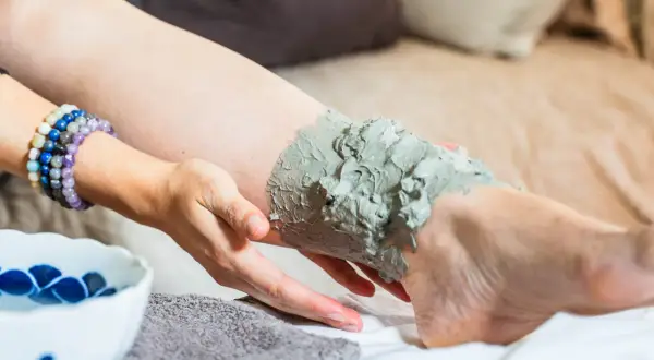 Application d'un cataplasme d'argile verte sur le genou pour un soin apaisant.