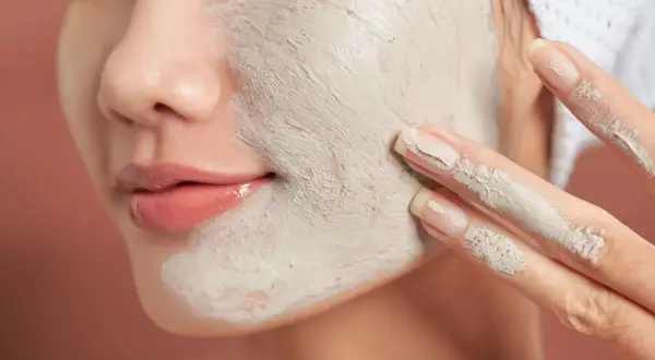 Une femme applique un masque d'argile sur son visage. Un tuto argile débutant pour une peau éclatante.