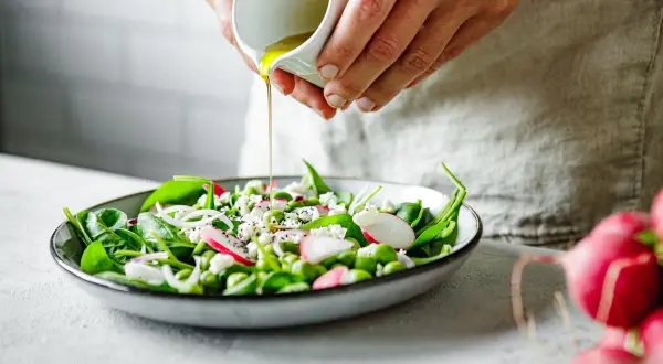 Salade fraîche avec vinaigrette versée, un plat sain pour soulager le foie. Épinards, radis, fèves edamame et fromage émietté.
