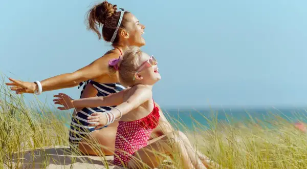 Mère et fille rient sur la plage, profitant du soleil. Un remède naturel contre la carence en vitamine D, même pour les plus jeunes.