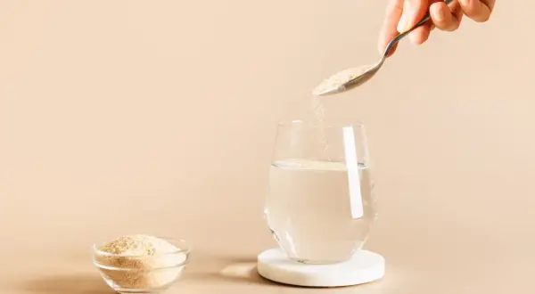 Une cuillère verse du psyllium dans un verre d'eau, une solution naturelle pour soulager la diarrhée.