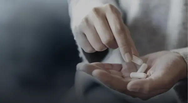 Une main tient des gélules. Quand prendre magnésium ? Le moment idéal dépend de vos besoins.