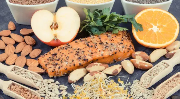 Assortiment d'aliments sains : saumon, amandes, fruits, graines. Une alimentation équilibrée est essentielle, surtout en cas d'hyperthyroïdie alimentation à éviter.