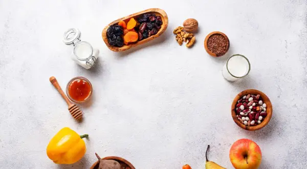 Un assortiment d'aliments bons pour l'estomac et les intestins : fruits secs, noix, graines de lin, haricots, lait, miel, poivron, betterave, pomme et poire.
