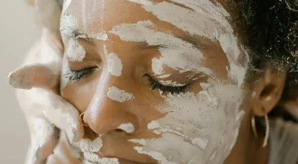 Une femme applique un masque d'argile verte sur son visage, espérant soulager son eczéma.