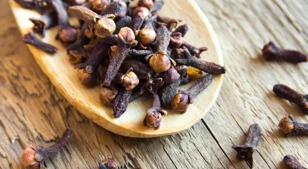 Girofles sur une cuillère en bois, évoquant leur potentiel dans la gestion de l'hypertension.