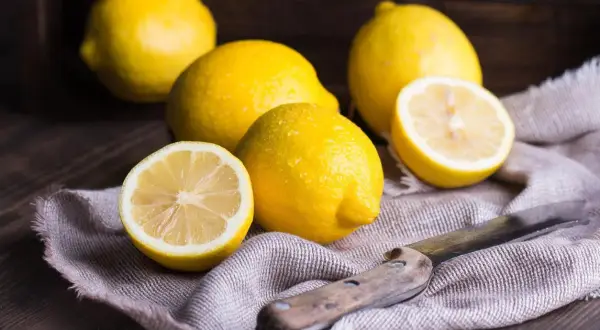 Citrons frais, coupés et entiers, sur un tissu, évoquant un remède de grand-mère contre le rhume de cerveau.