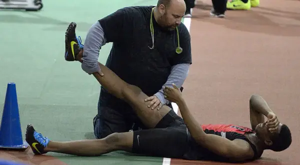 Un athlète reçoit des soins pour une jambe, peut-être pour comment éviter les crampes pendant l'effort.