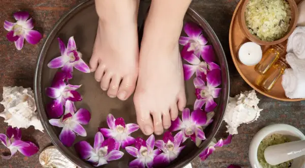 Pieds dans un bain de fleurs d'orchidée et de sel d'Epsom pour un moment de détente.