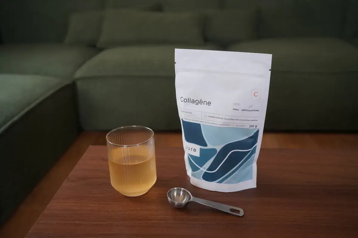 Un verre de boisson au collagène et sa dosette à côté d'un sachet, idéal pour savoir quand prendre le collagène.