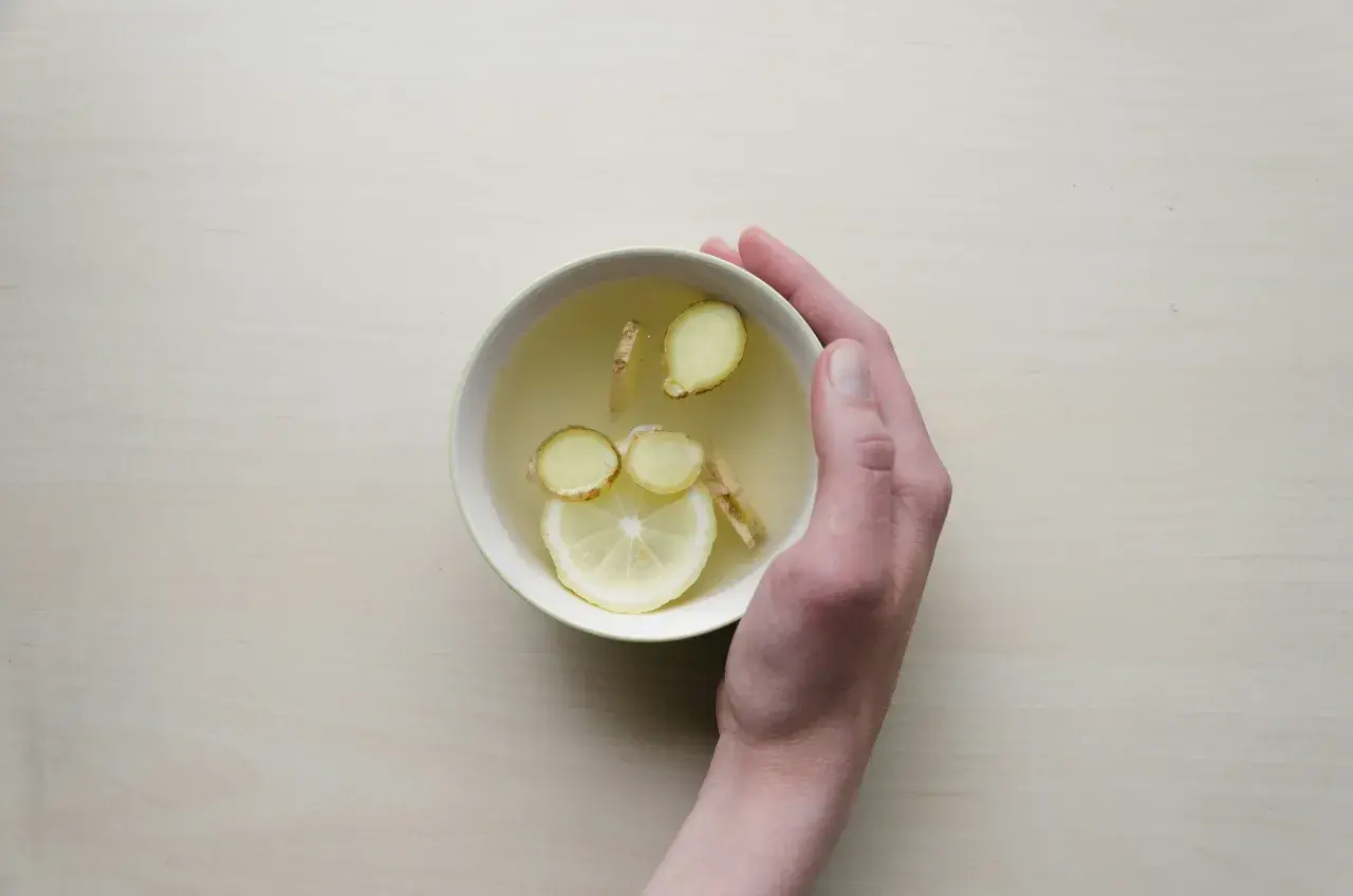 Une main tient un bol de tisane au citron et au gingembre, une boisson réconfortante pour comment prendre soin de son foie.