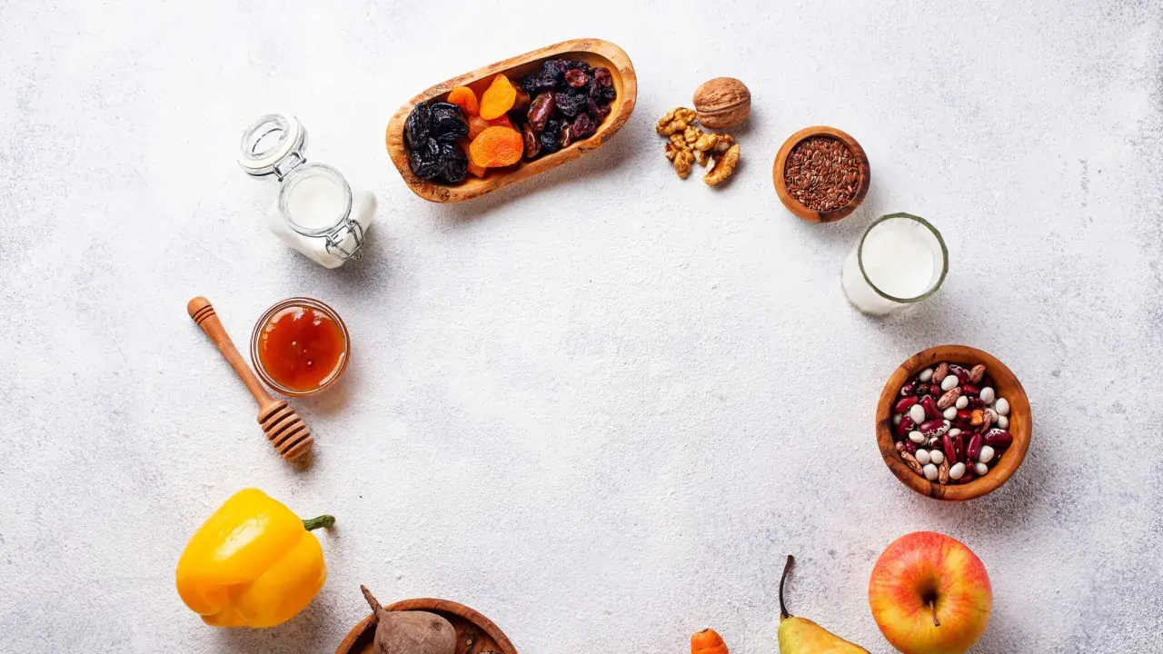 Un assortiment d'aliments bons pour l'estomac et les intestins : fruits secs, noix, graines de lin, haricots, lait, miel, poivron, betterave, pomme et poire.