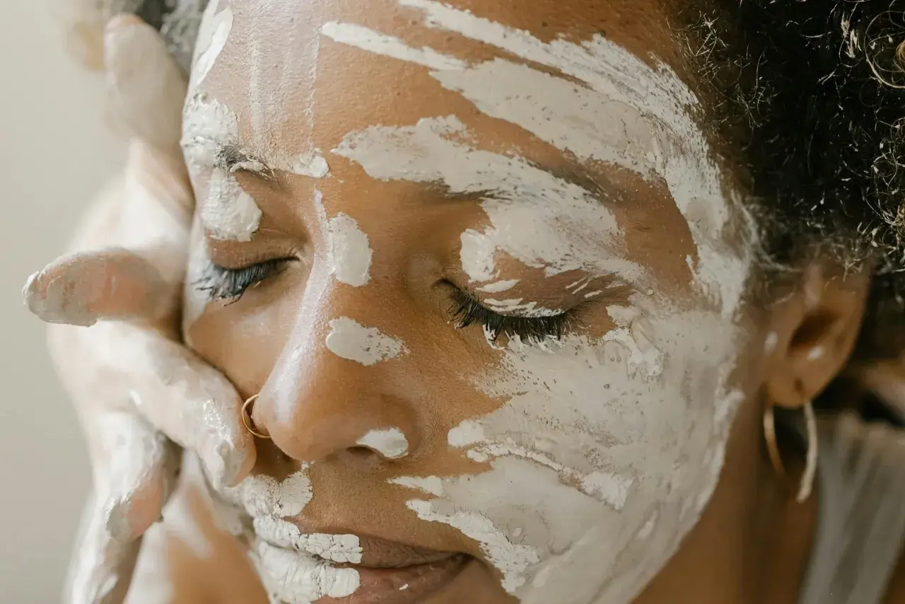 Une femme applique un masque d'argile verte sur son visage, espérant soulager son eczéma.