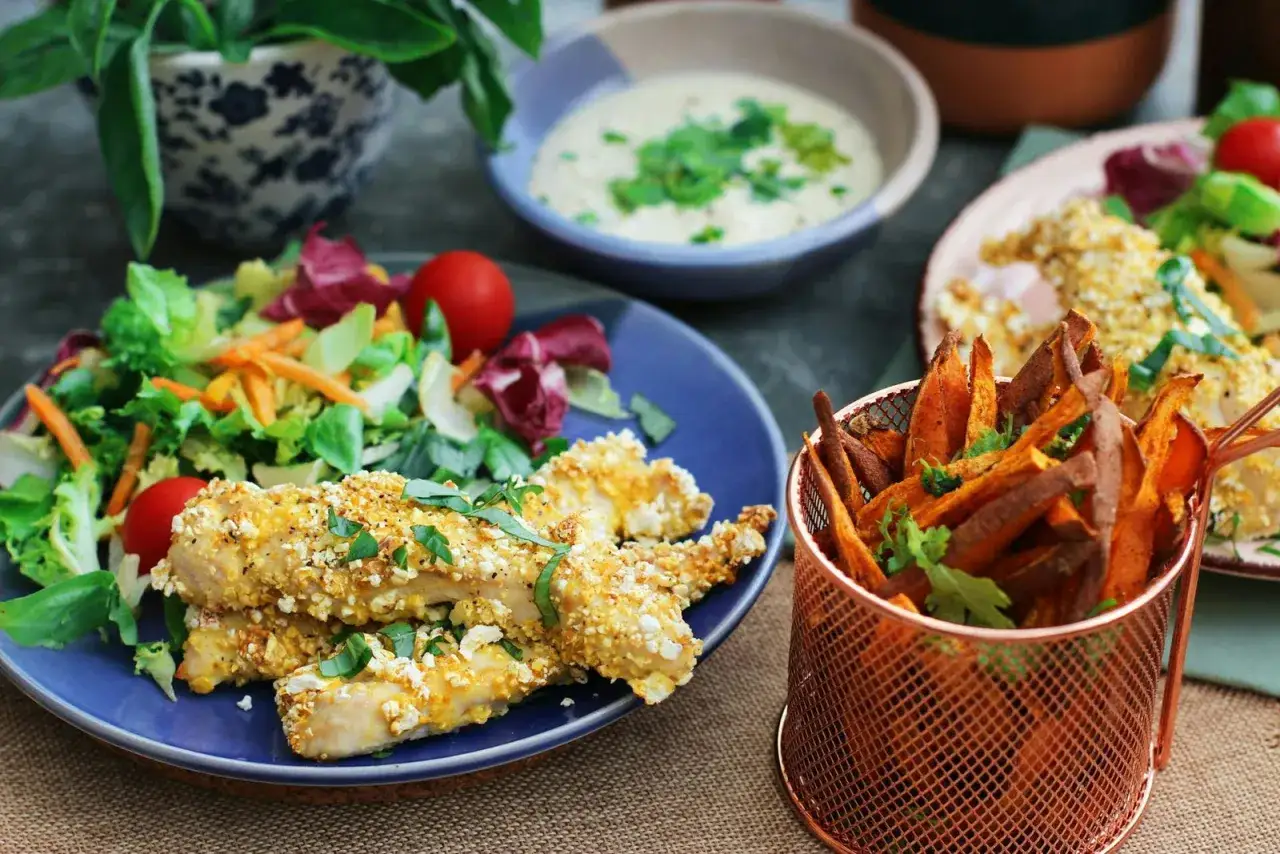 Poulet pané sans gluten, frites de patate douce et salade fraîche. Un repas savoureux pour ceux qui gèrent l'intolérance au gluten.