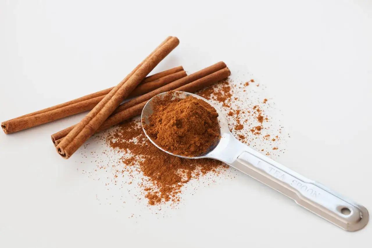 Bâtonnets de cannelle et une cuillère remplie de poudre, rappelant les dangers de la cannelle si consommée en excès.