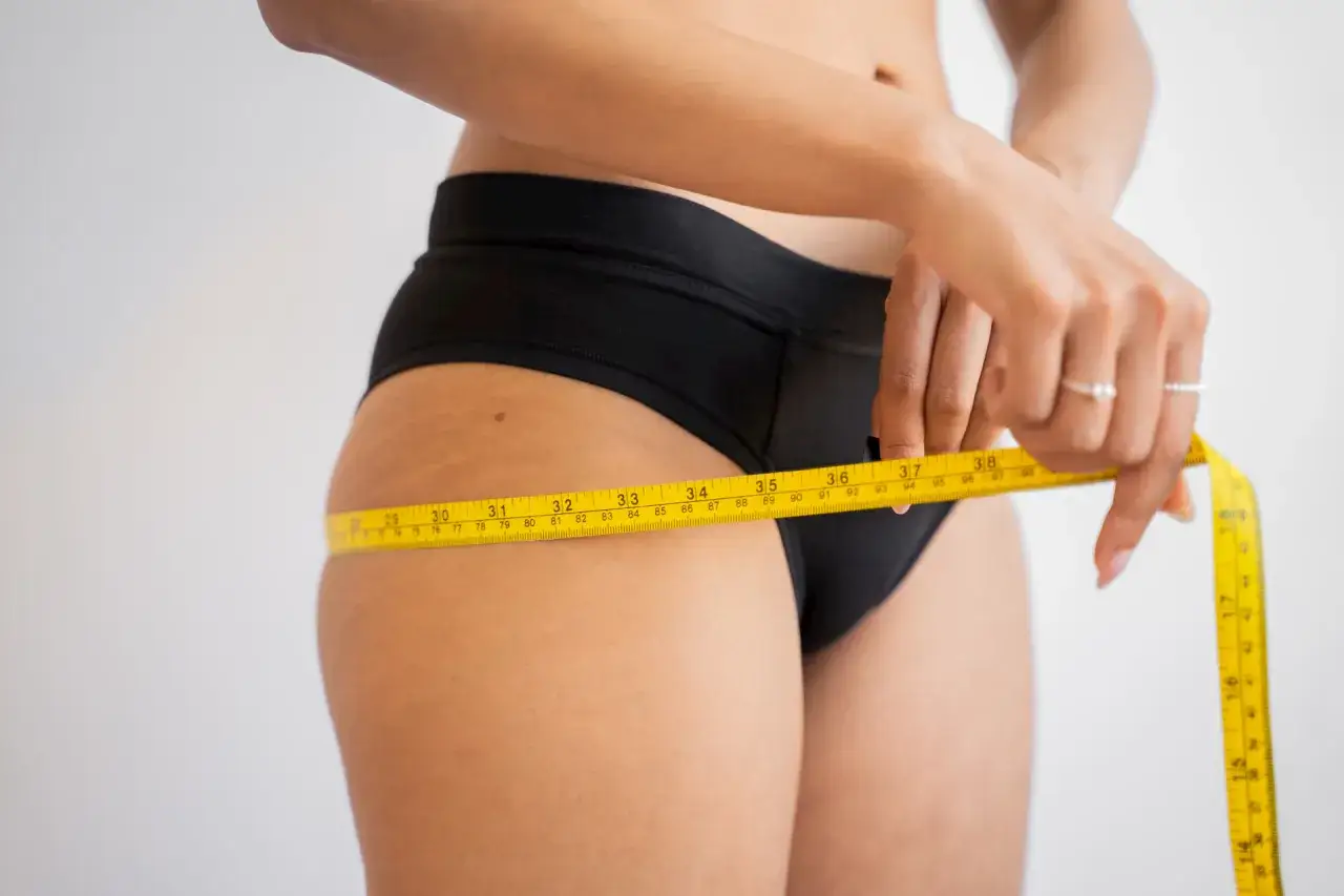 Femme mesurant sa taille, préoccupée par une éventuelle carence en vitamine D et une prise de poids.