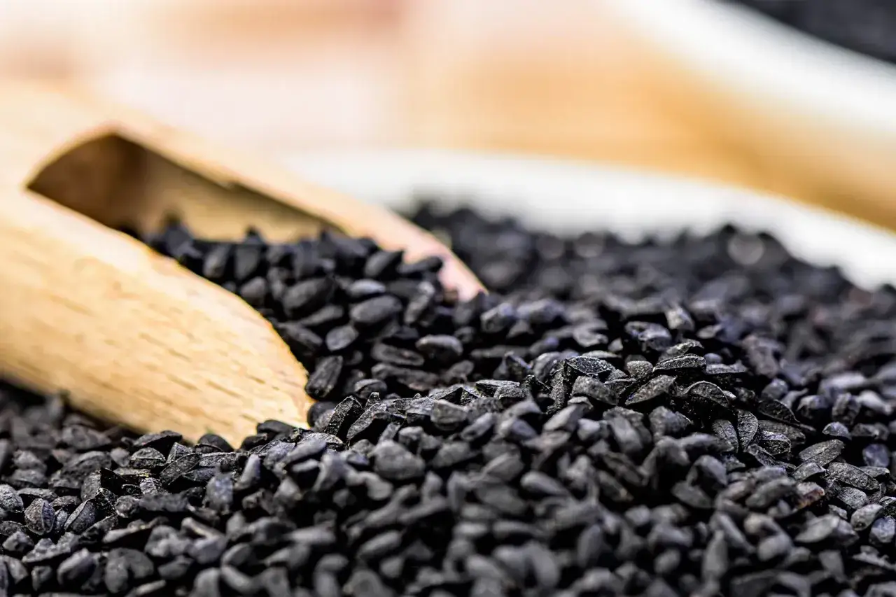 Graine de nigelle, petite merveille noire aux multiples vertus, captur&eacute;e dans une cuill&egrave;re en bois.