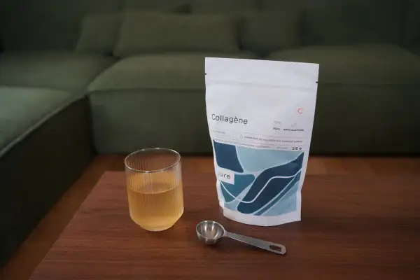 Un verre de boisson au collagène et sa dosette à côté d'un sachet, idéal pour savoir quand prendre le collagène.